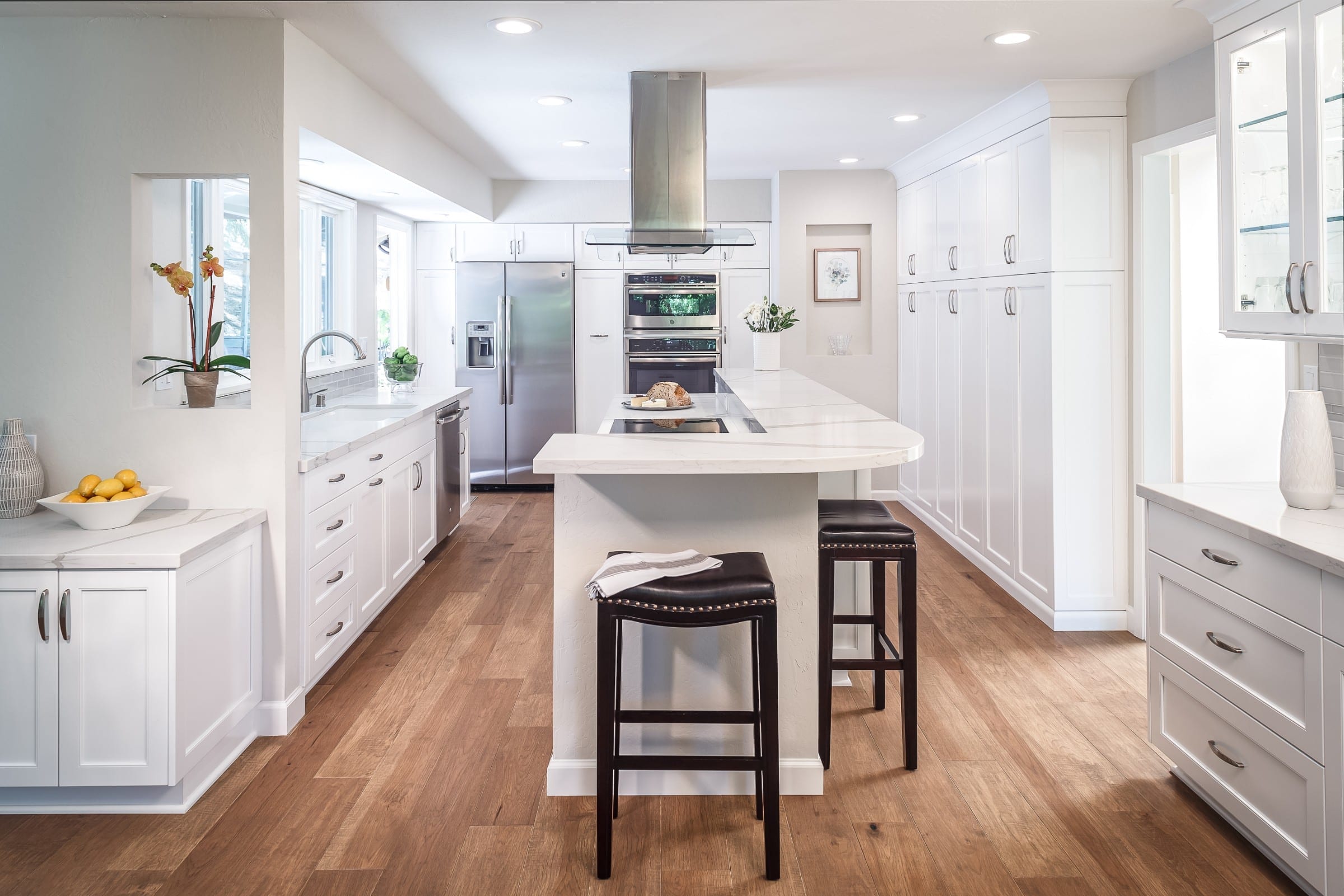 white kitchen with long island and wood stool seating big overhang seating on two sides