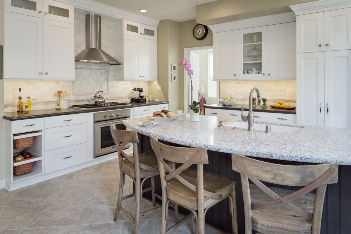 white kitchen with white and black island and wood chair seating