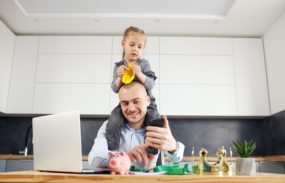 father with child on shoulder work from home in kitchen