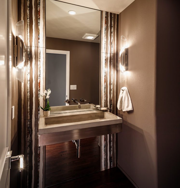 Powder room with eggplant colored tile and dramatic lighting