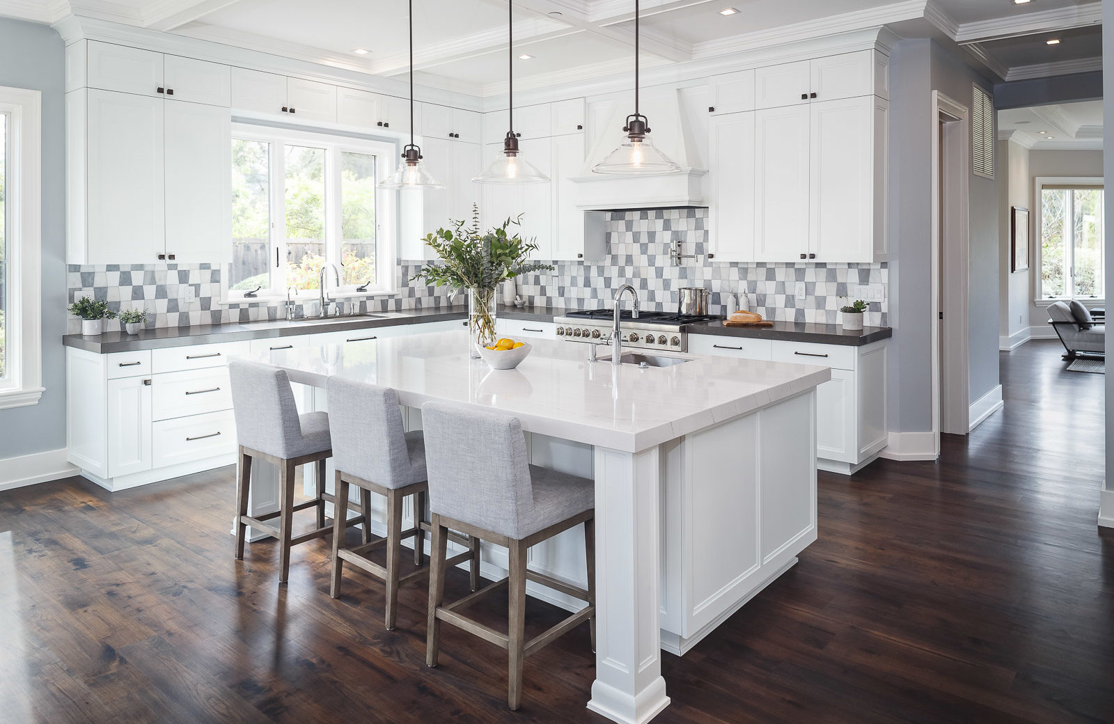 large white kitchen with large white island 3 chairs seating wood floors