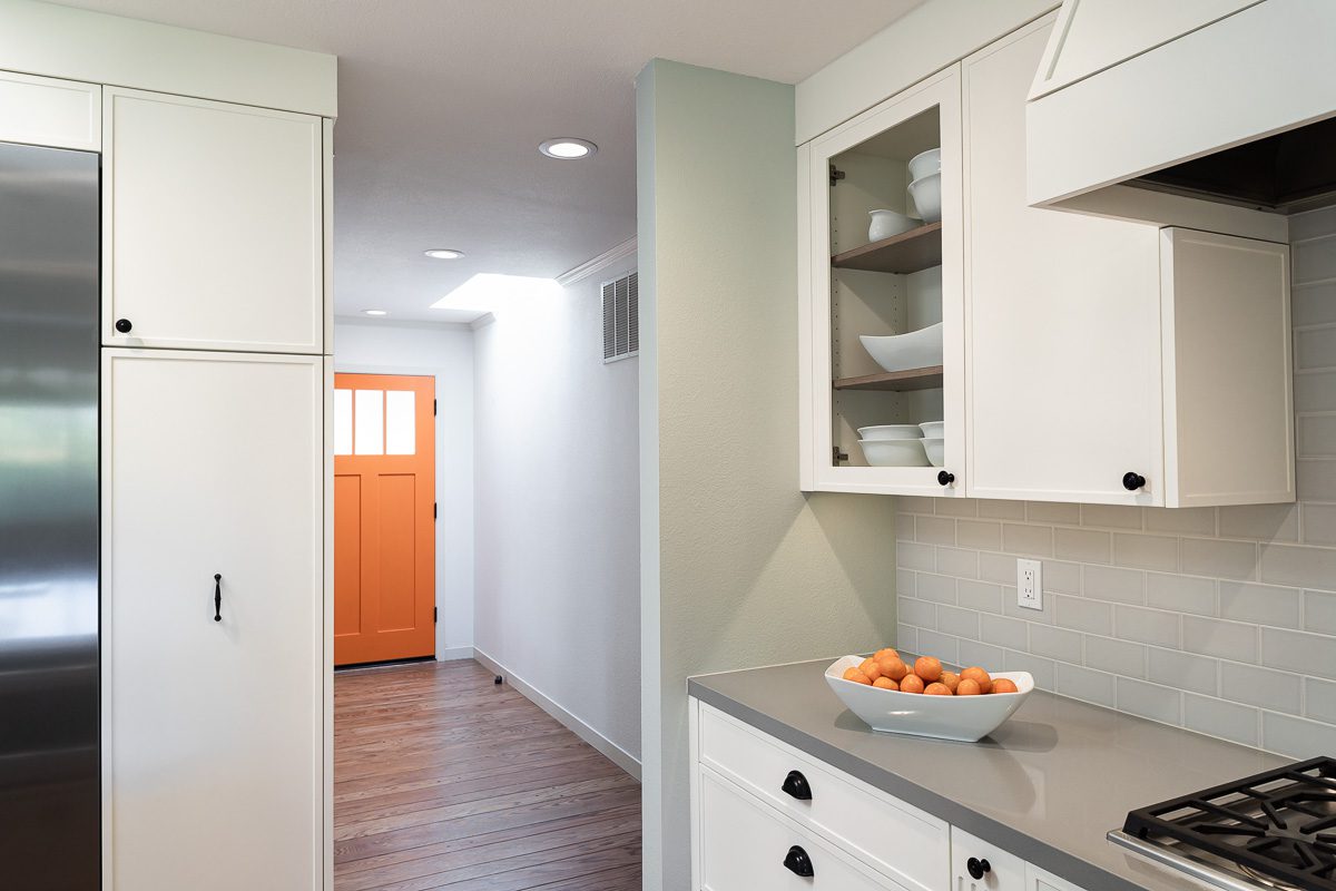 white painted cabinets and modern orange front door