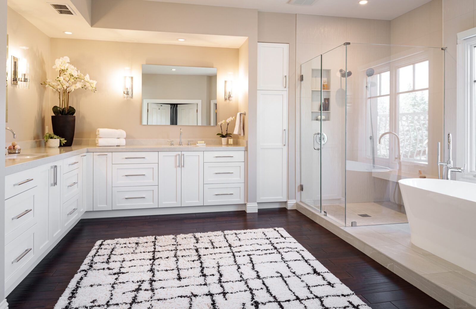 large primary bathroom with white painted cabinets and dark wood floors and rug after
