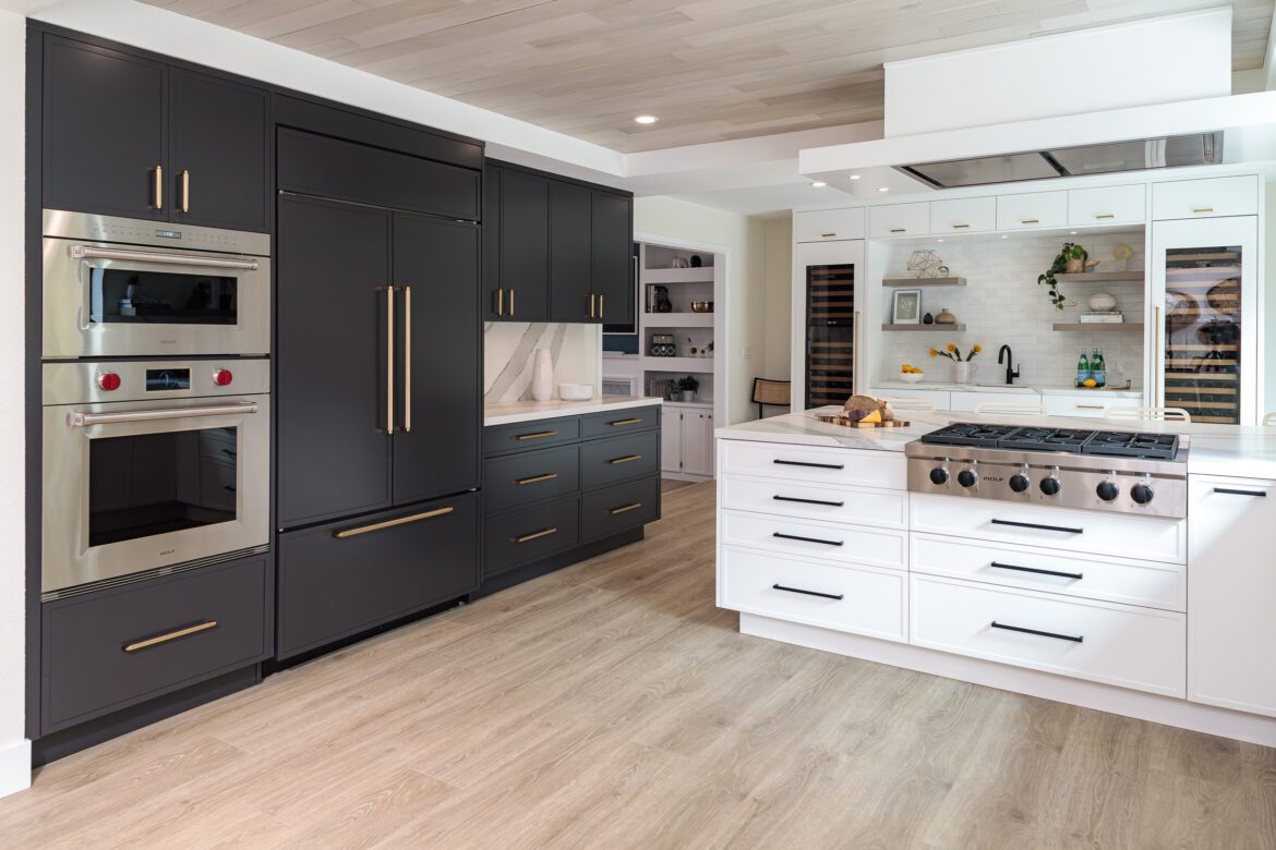 Large kitchen with Charcoal and white cabinets, paneled Sub Zero fridge and freezer, ceiling mounted hood, light LVP floors; two toned cabinets