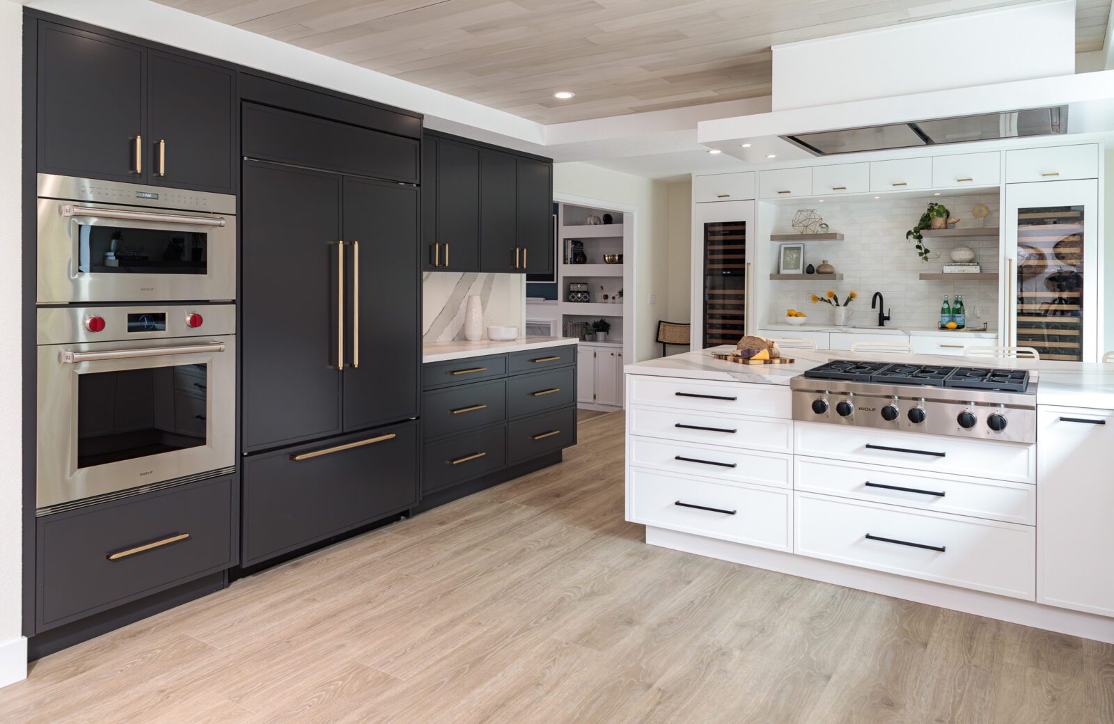 Large kitchen with Charcoal and white cabinets, paneled Sub Zero fridge and freezer, ceiling mounted hood, light LVP floors; two toned cabinets