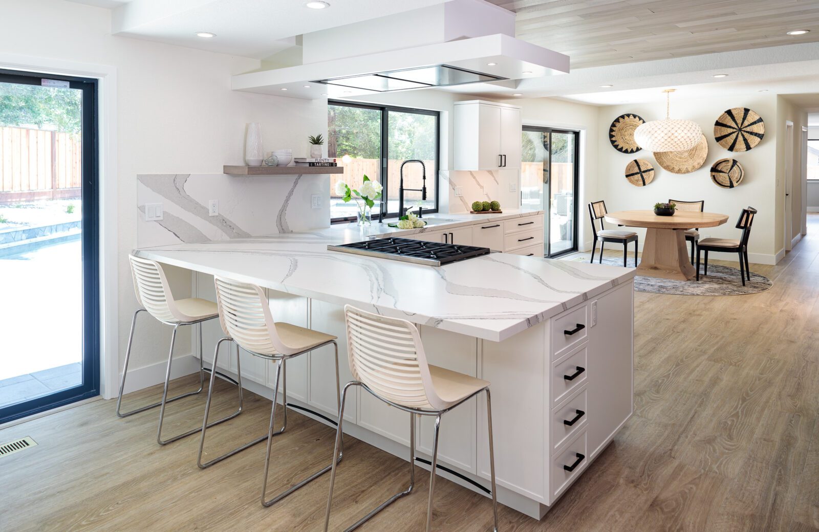 modern kitchen remodel with light LVP floors, white peninsula with space for white seating for 3, wood ceiling panels