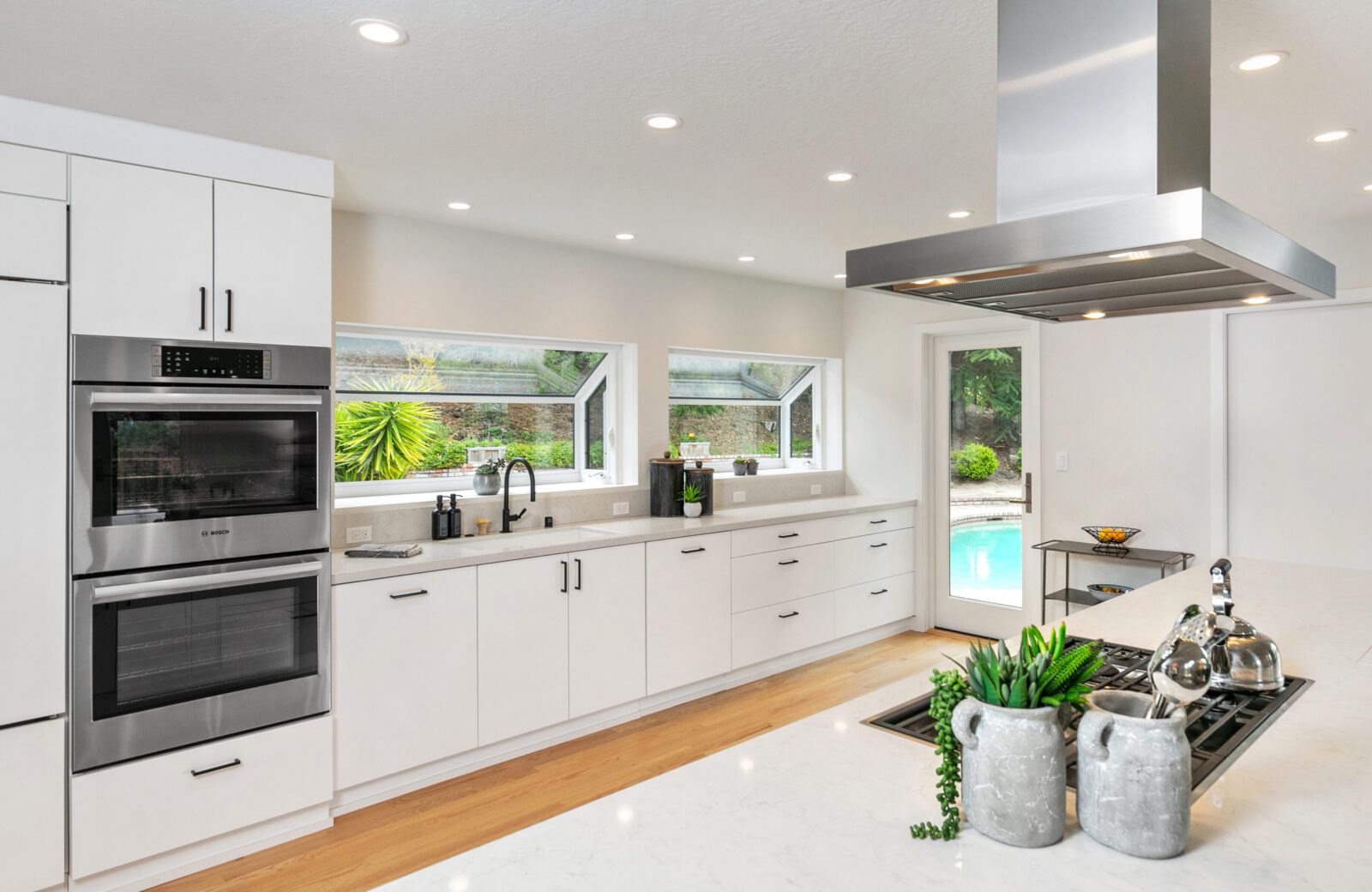 white kitchen remodel with double ovens and cooktop wood floors