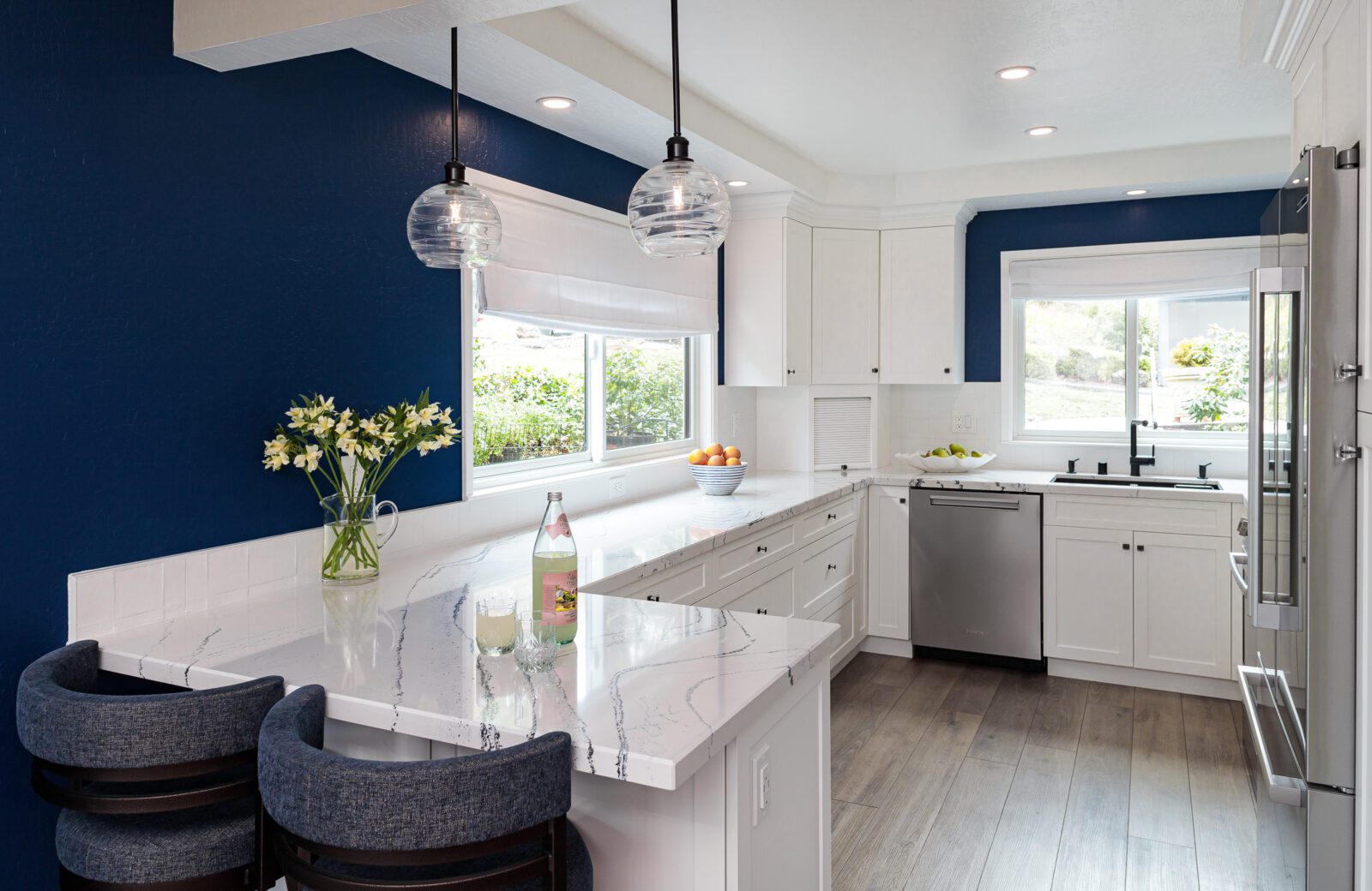 Small blue white kitchen remodel with peninsula seating lvp floor blue accent wall