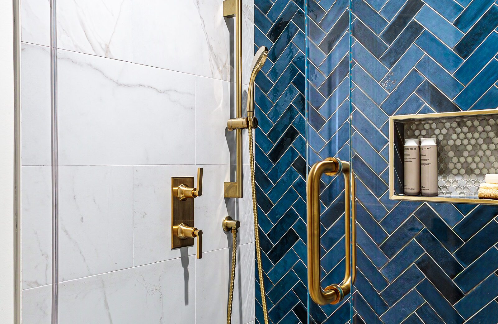 satin brass plumbing fixtures, blue herringbone tile wall, shower niche