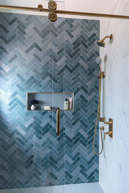 hall bath remodel with blue herringbone tile shower wall, satin brass plumbing fixtures