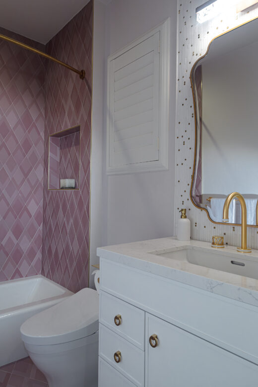 girls bathroom with pink shower tile, satin brass fixtures, shower niche