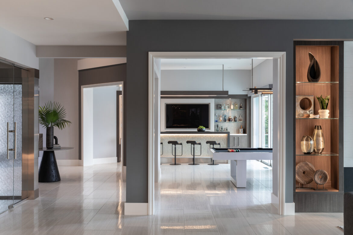 custom home bar with large screen TV, lighted island and flyover panel, art niche