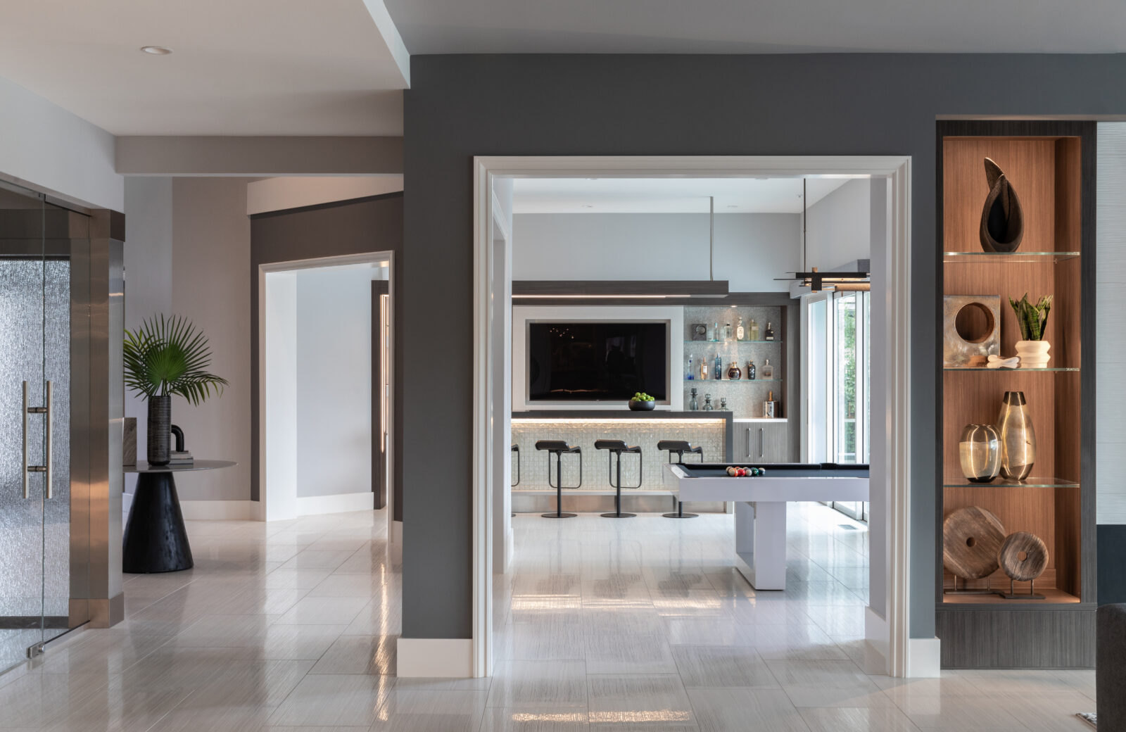 custom home bar with large screen TV, lighted island and flyover panel, art niche